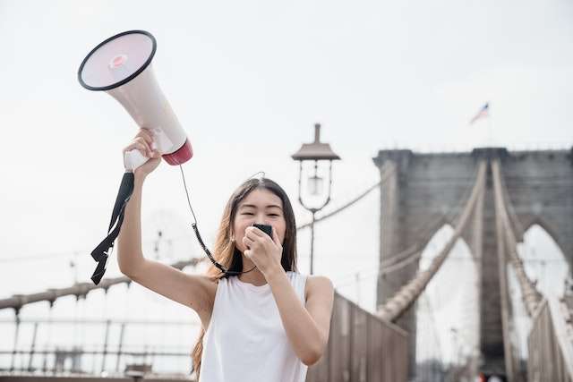 Gen Z mass protesting with a megaphone on San Francisco Bridge