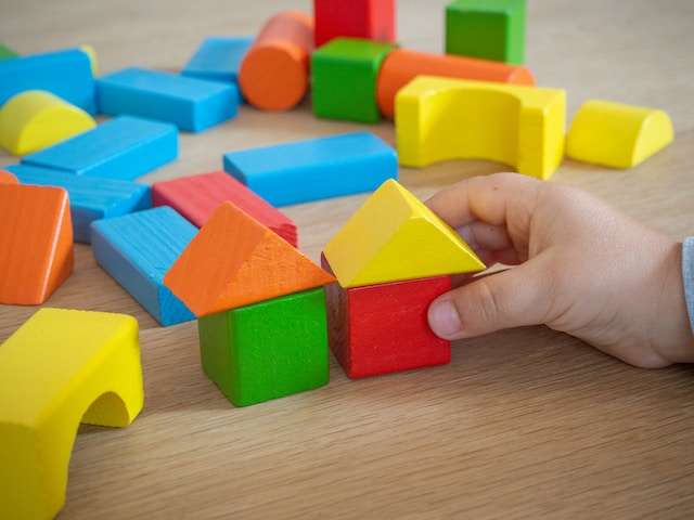 Child playing with colored wooden building blocks