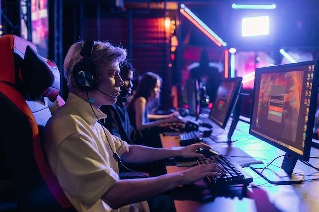 Professional gamers in a competitive esports tournament wearing gaming headsets while playing video games on their computers