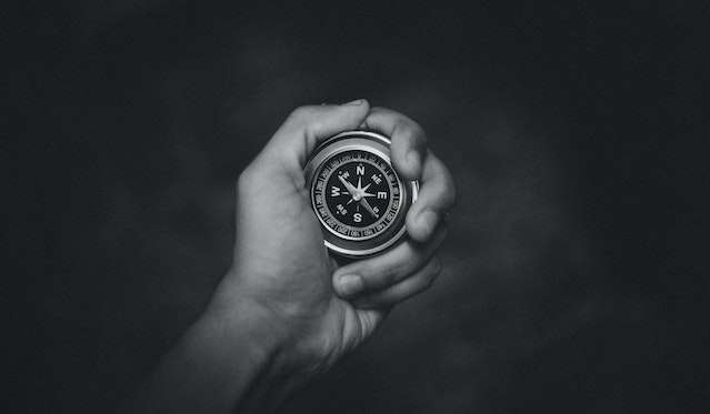 Black and white image of a hand with a compass
