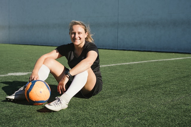 Female soccer player sitting down on the soccer field